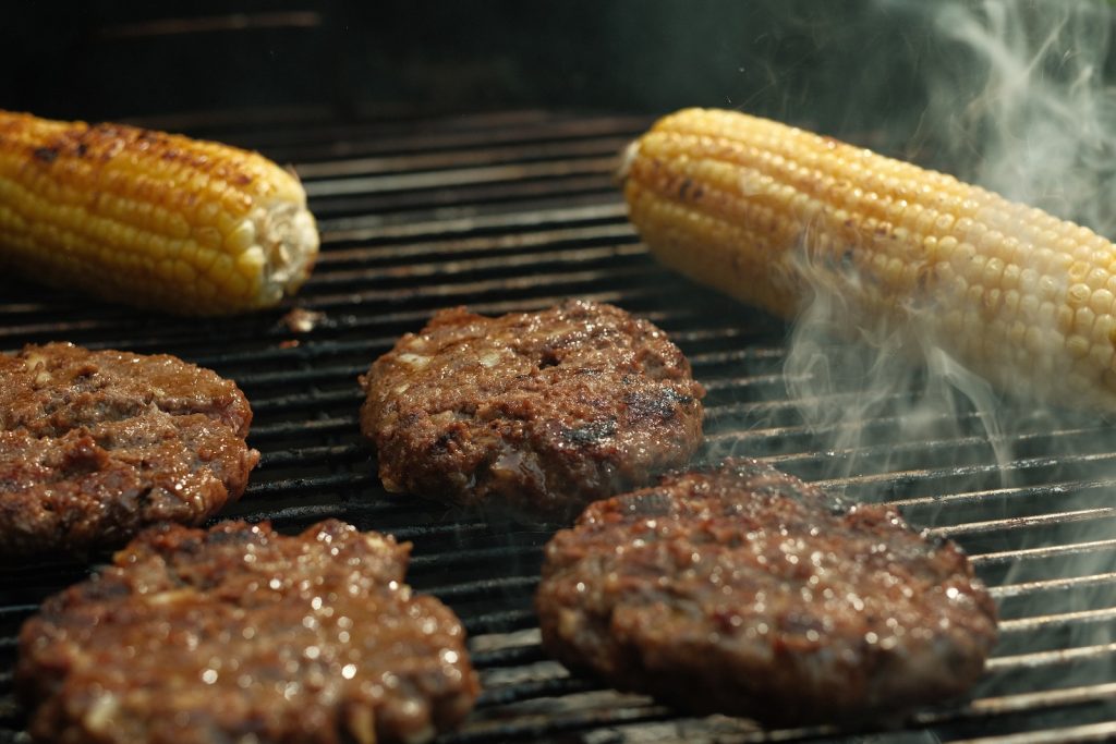 hamburgers and hamburger patties cooking on a grill